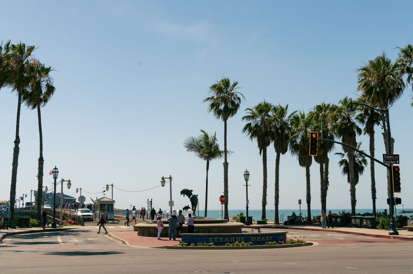 Stearns Wharf entrance in Santa Barbara with dolphin statue, palm trees, and ocean views on a sunny day