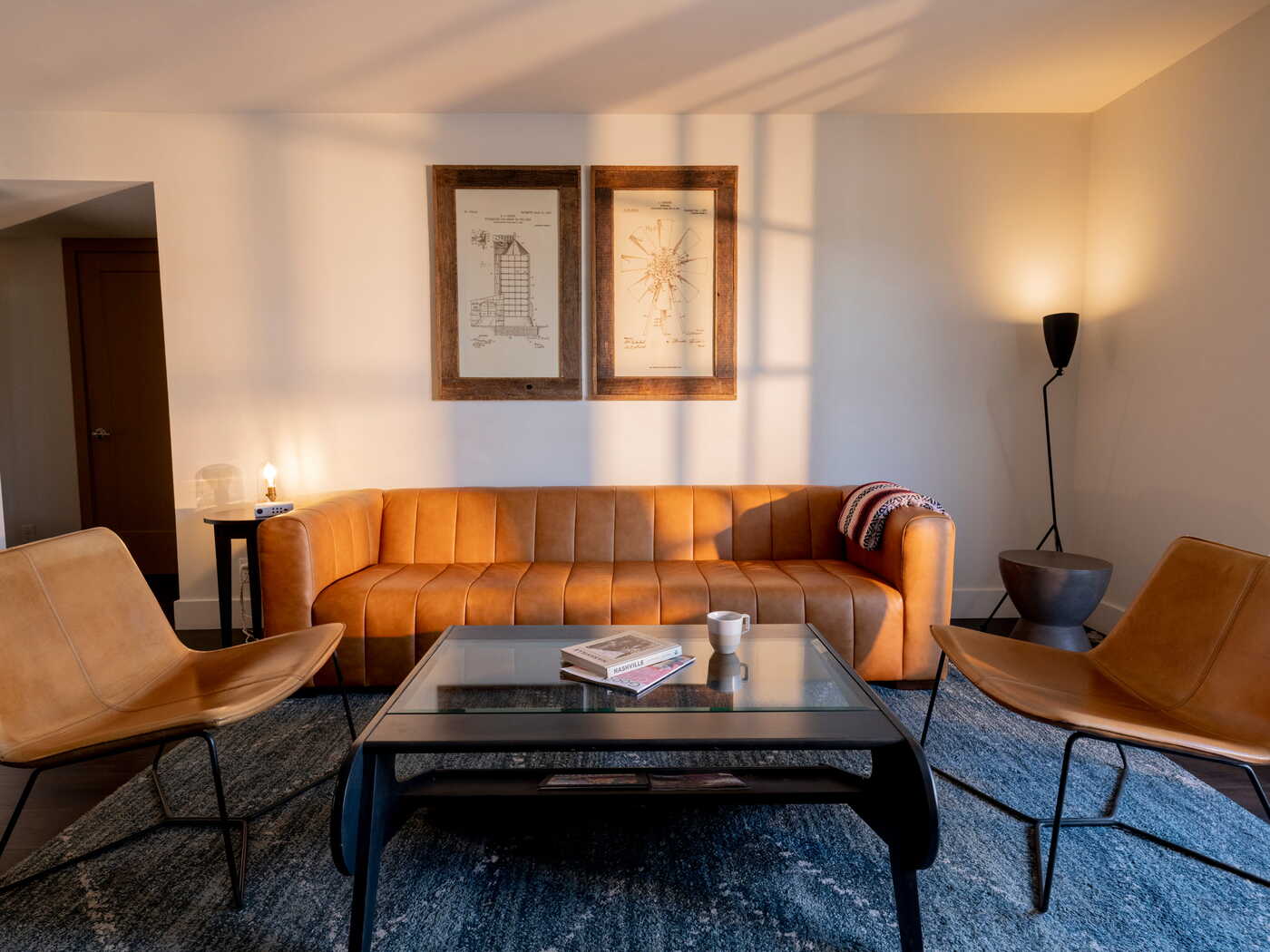 Stylish Bode hotel living room featuring a tan leather channel-tufted sofa, leather chairs, and framed patent artwork