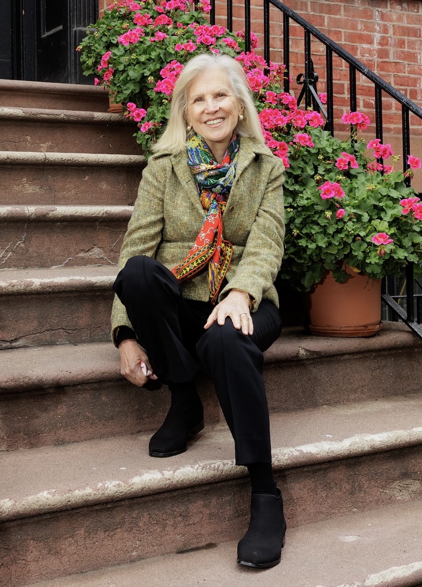 Regina Skyer, founder and managing partner of Skyer Law, sitting on a stoop with pink flowers in the background