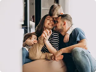 Happy family of four hugging and smiling together indoors.