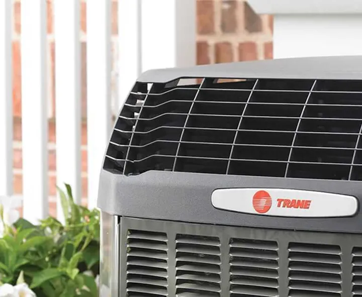 Close-up of a Trane HVAC outdoor unit with visible front vents and brand logo.