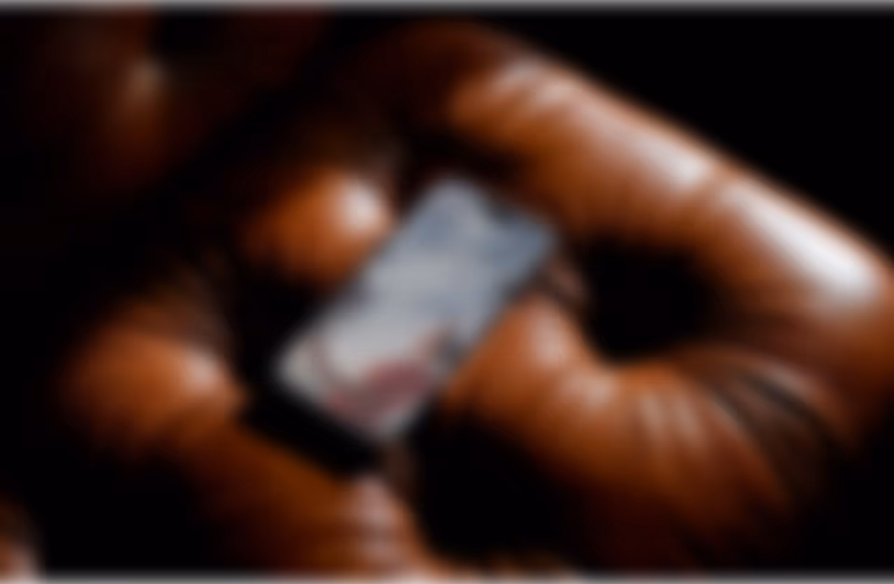 Mão segurando um smartphone com uma tela desfocada.