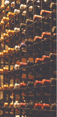 Várias garrafas de vinho armazenadas horizontalmente em uma adega de metal.