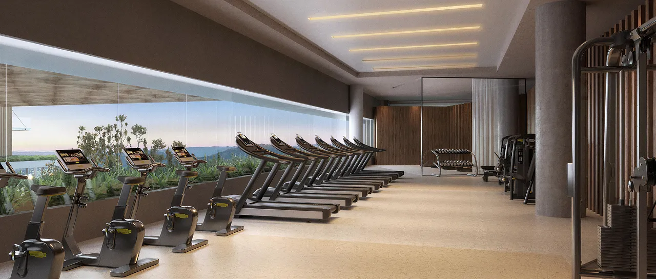 Academia moderna com fileira de bicicletas ergométricas e esteiras junto a parede de vidro com vista para o pôr do sol.