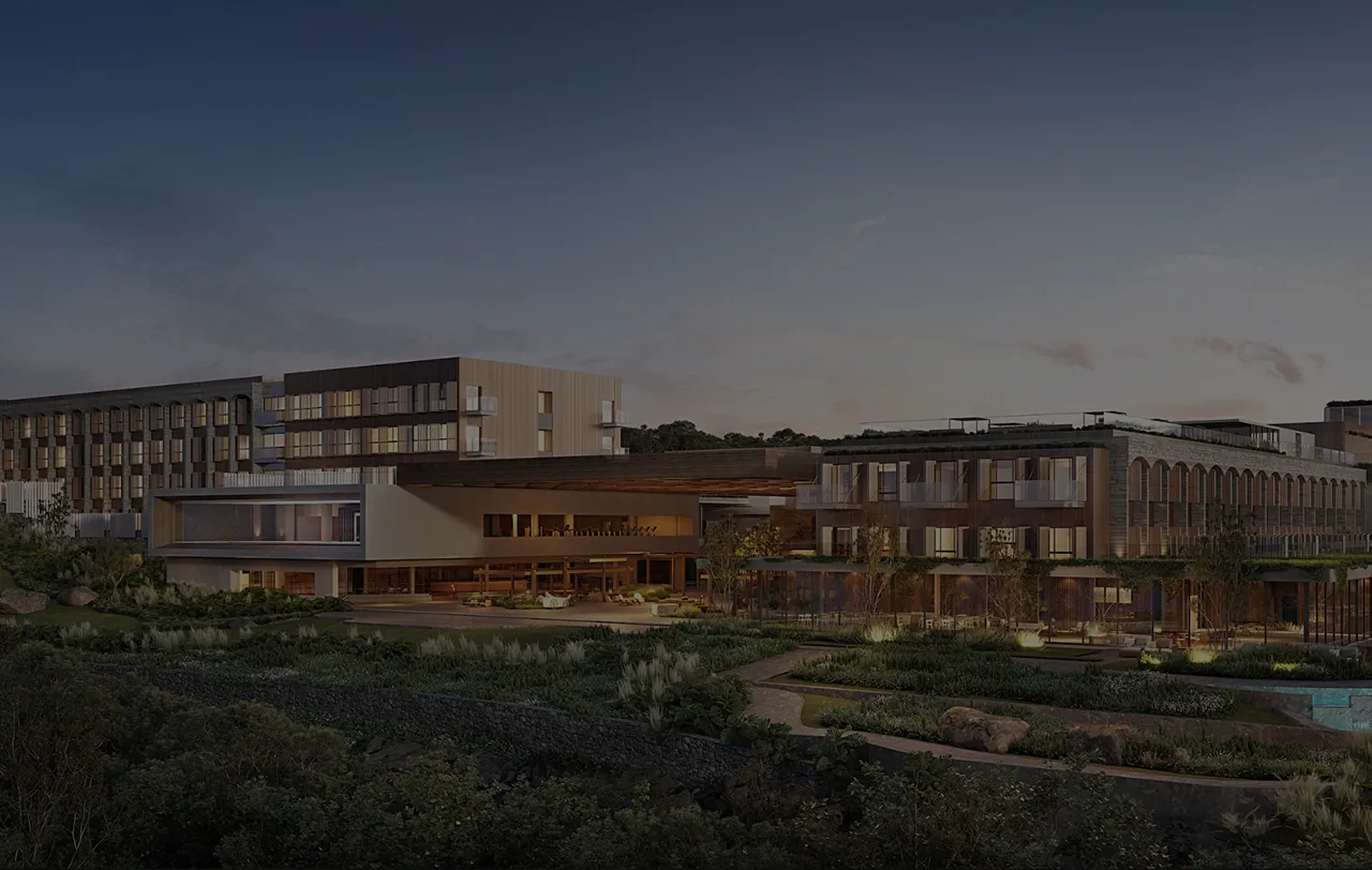 Vista noturna de um complexo moderno de edifícios residenciais com iluminação suave e áreas verdes ao redor.