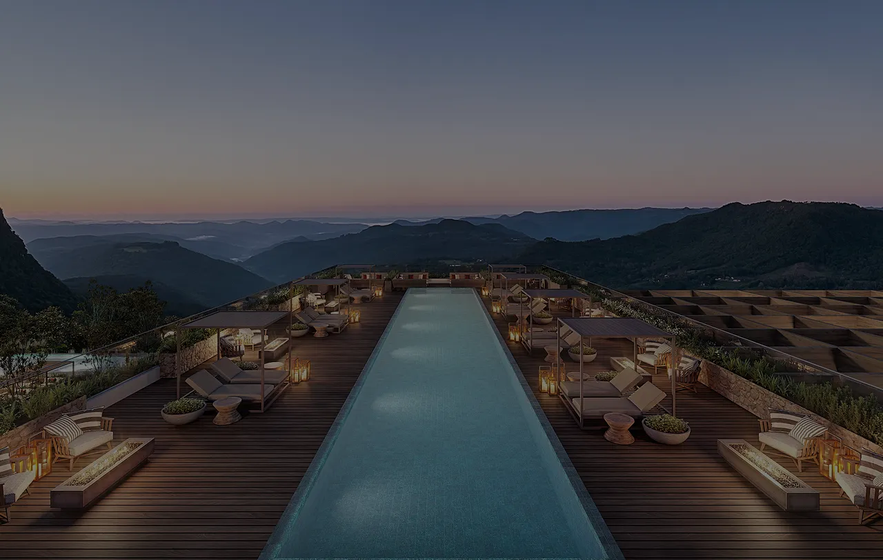 Piscina retangular com espreguiçadeiras e gazebos à noite, com vista para montanhas ao pôr do sol.