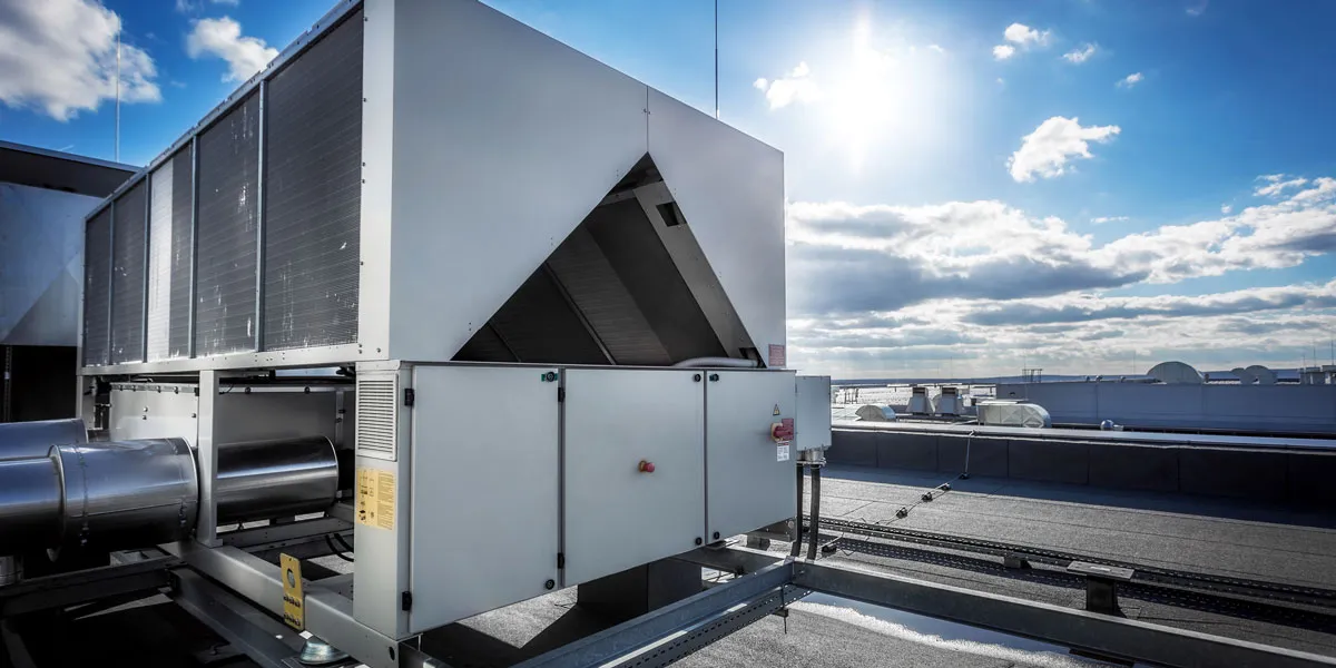 Large industrial HVAC unit on a rooftop under a bright blue sky with some clouds.