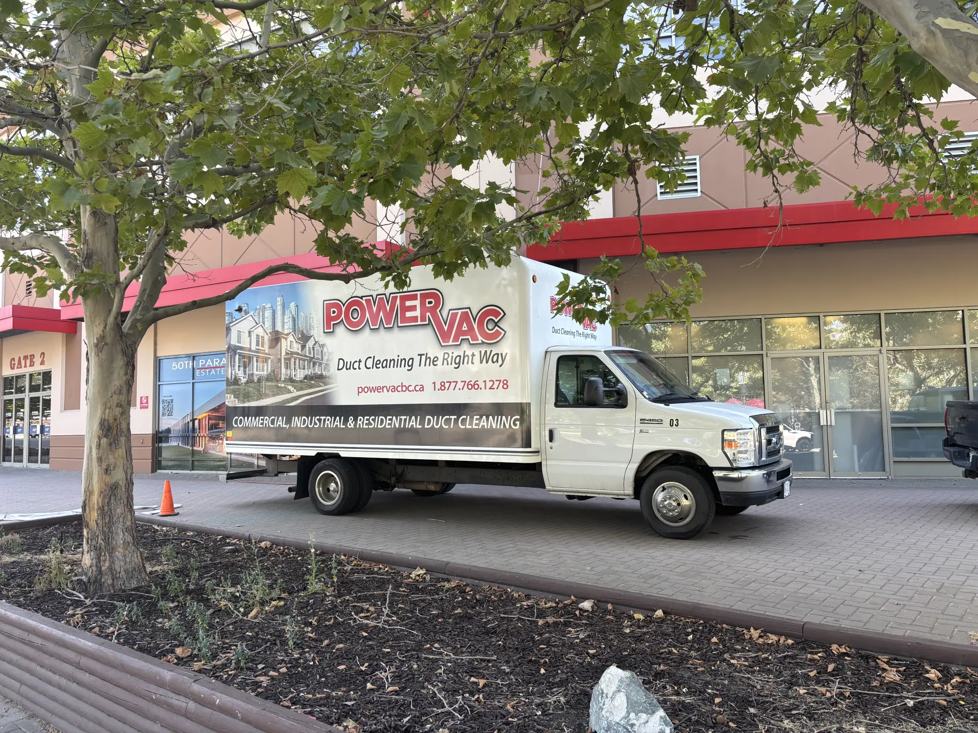 White Power Vac duct cleaning truck parked on a paved sidewalk near a building entrance labeled Gate 2.