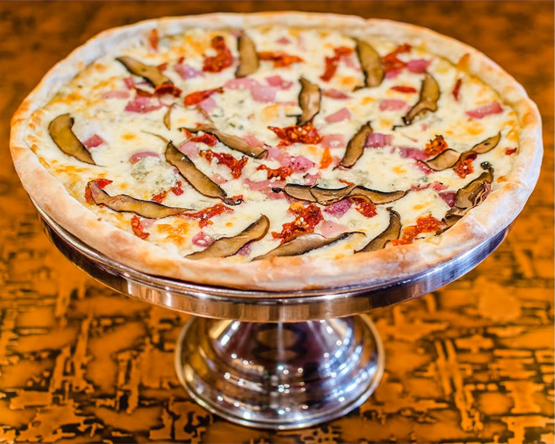 A pizza with mushrooms and ham on a silver platter.