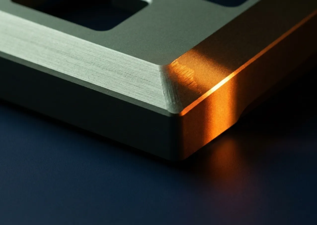 Close-up of a machined metal part lit by an orange glow on a dark background.