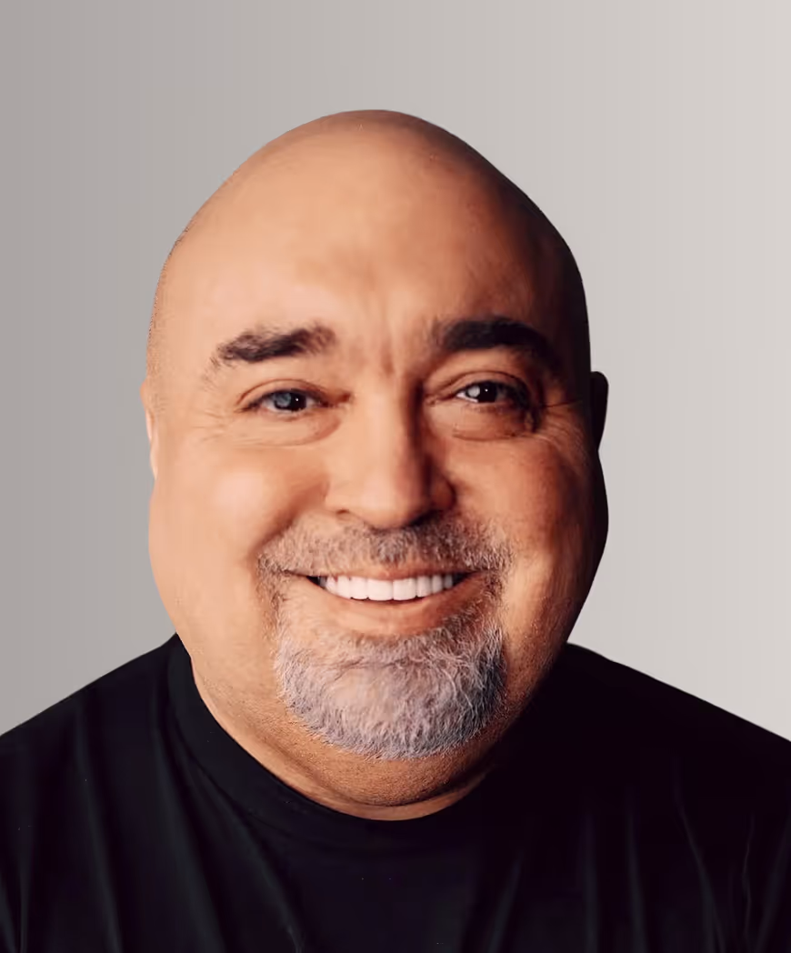 Smiling bald man with gray goatee wearing a black shirt against a light gray background.