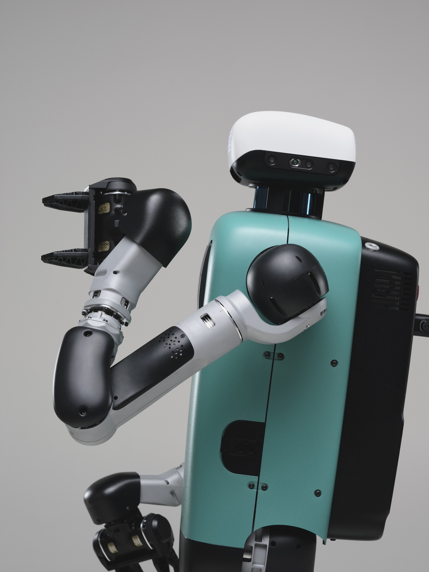 Close-up of a teal and black humanoid robot with a white head and articulated arms against a gray background.