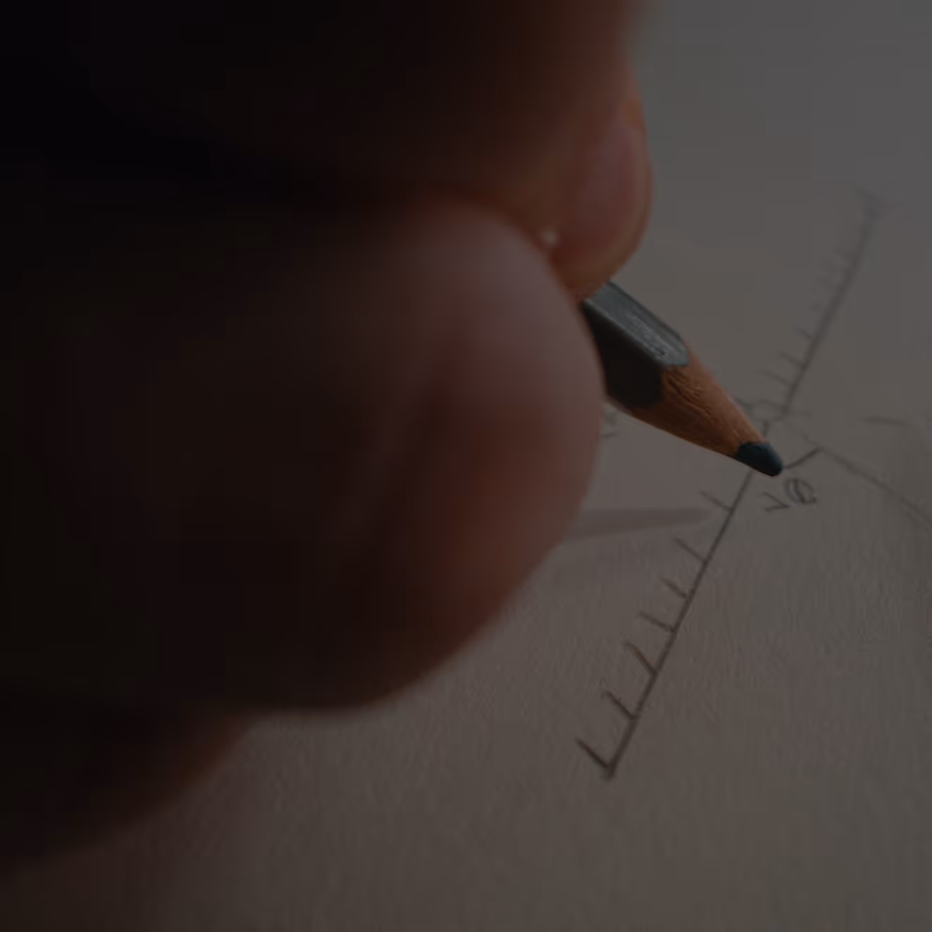 Hand holding a pencil drawing a detailed geometric diagram with lines and measurements on paper.