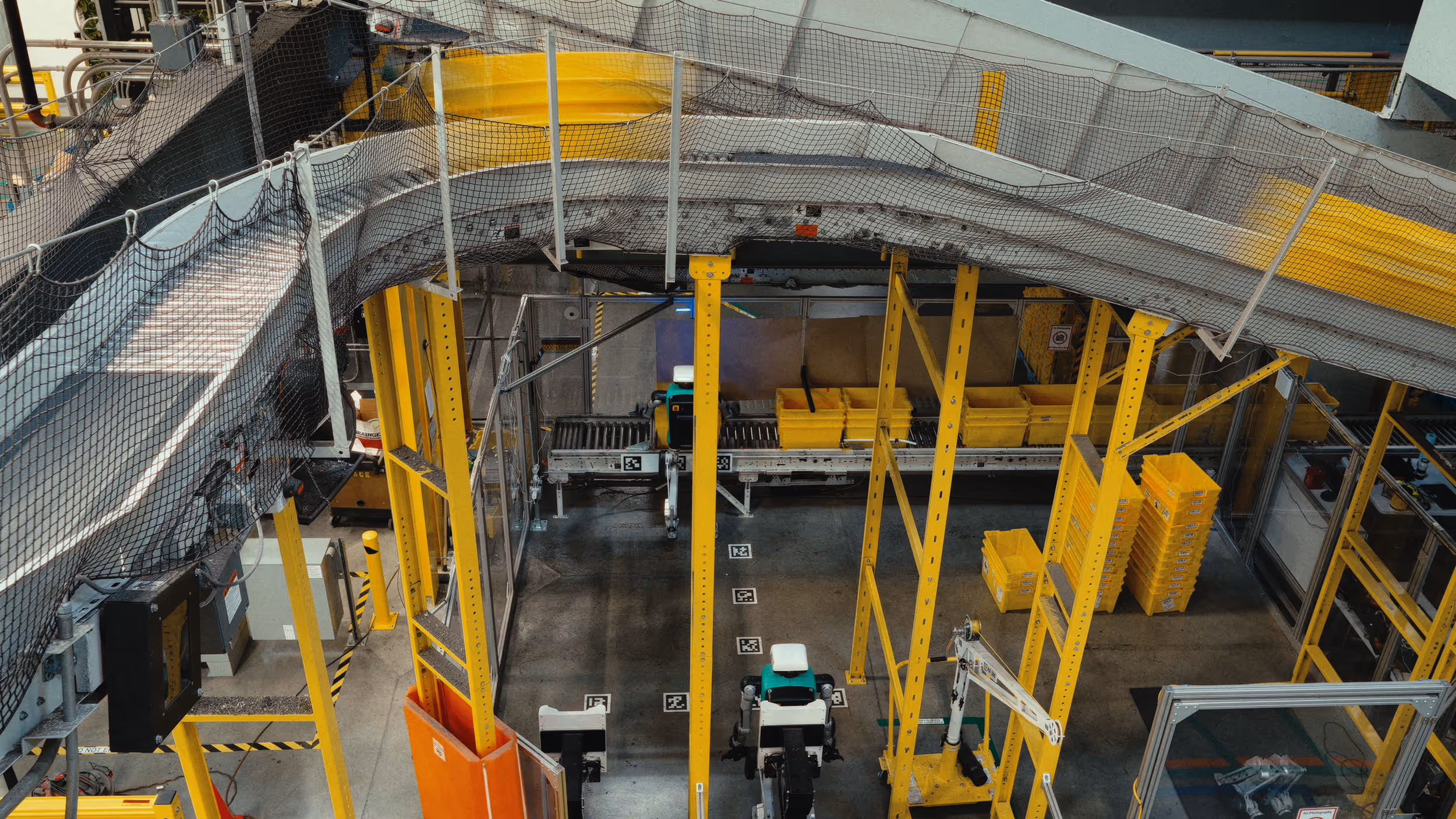 Industrial automation setup with yellow metal framework, conveyor belts, and robotic arms in a factory.