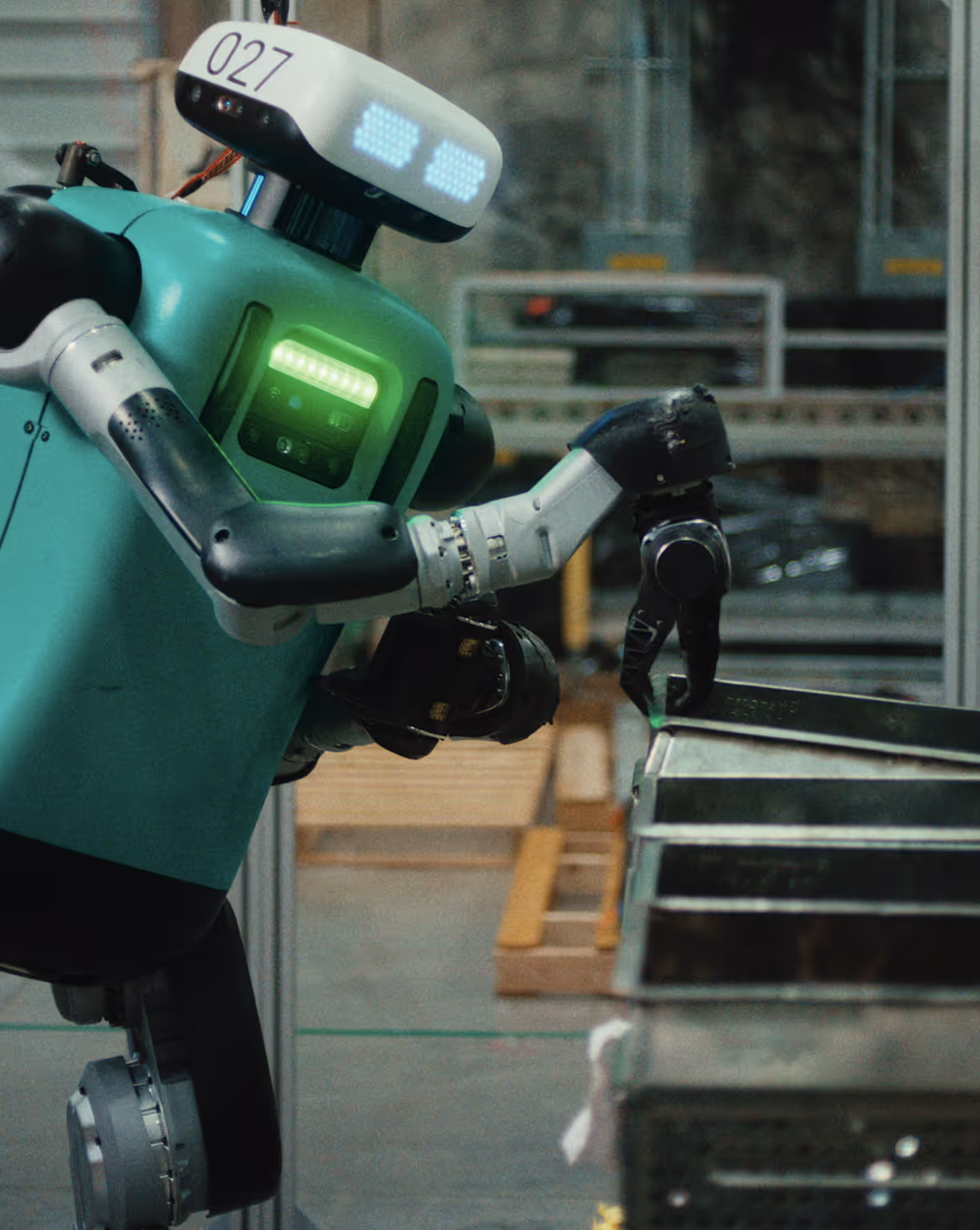 Robot with digital eyes and green chest light using mechanical hand to interact with stacked metal trays.