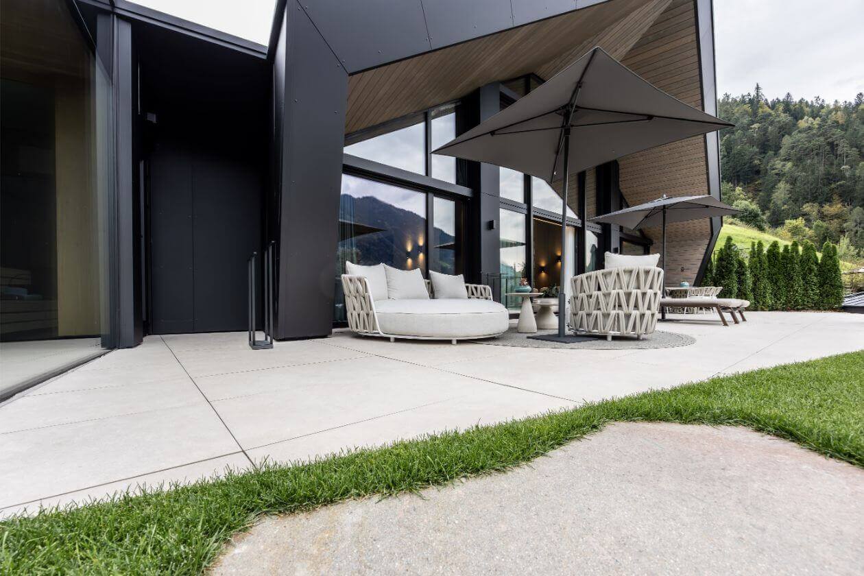 Moderner Terrassenbereich mit hellen Fliesen und überdachtem Sitzplatz