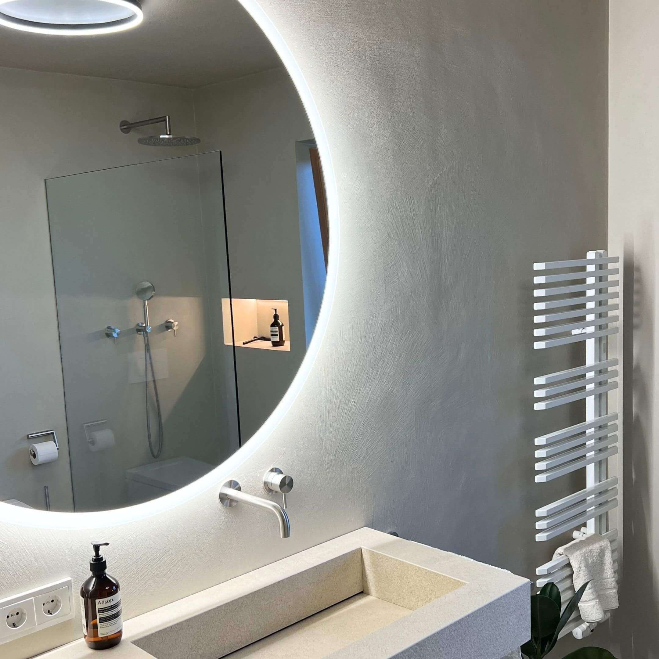 Badezimmer mit fugenloser Wandbeschichtung und rundem Spiegel