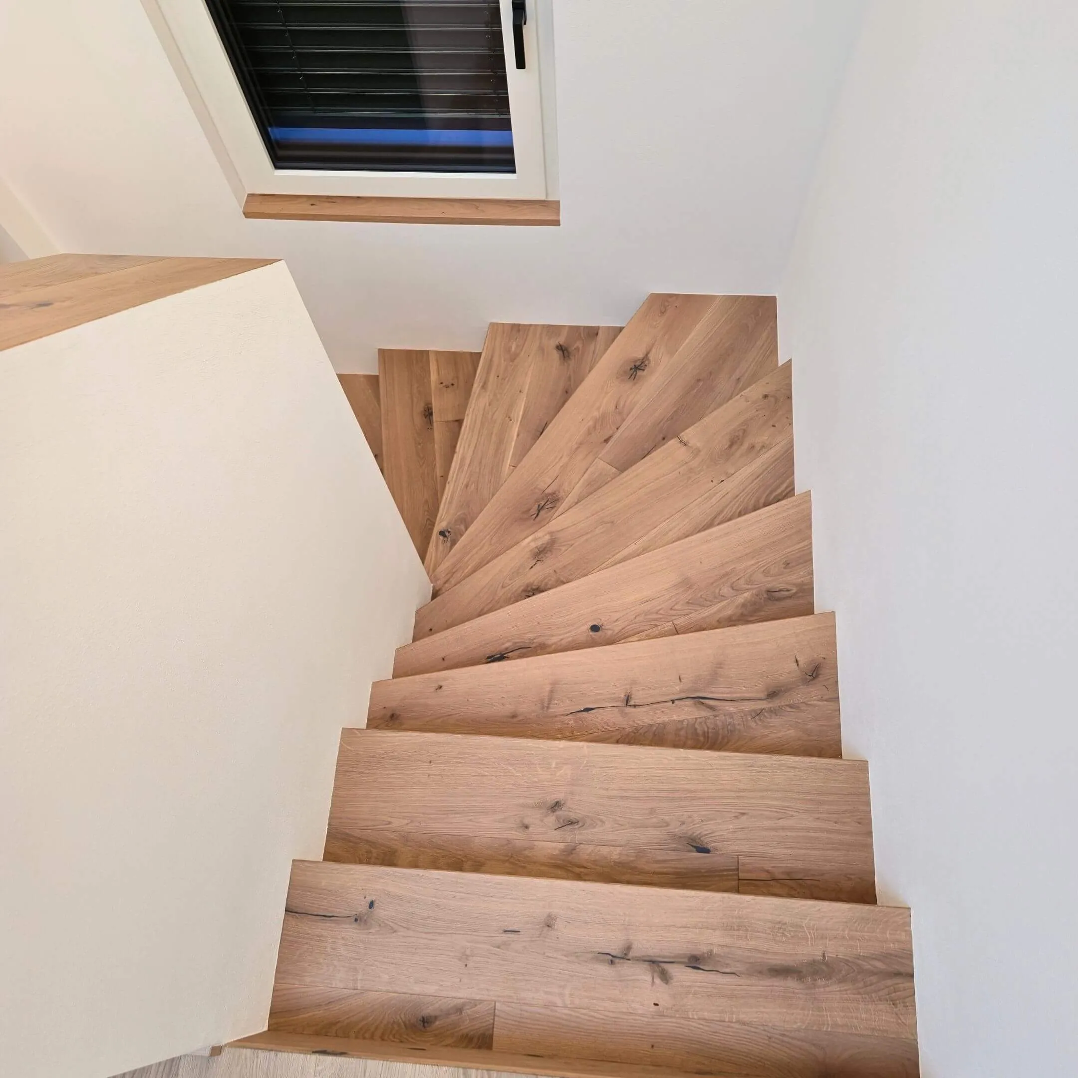 Holztreppe mit geölten Stufen und minimalistischer Wandführung