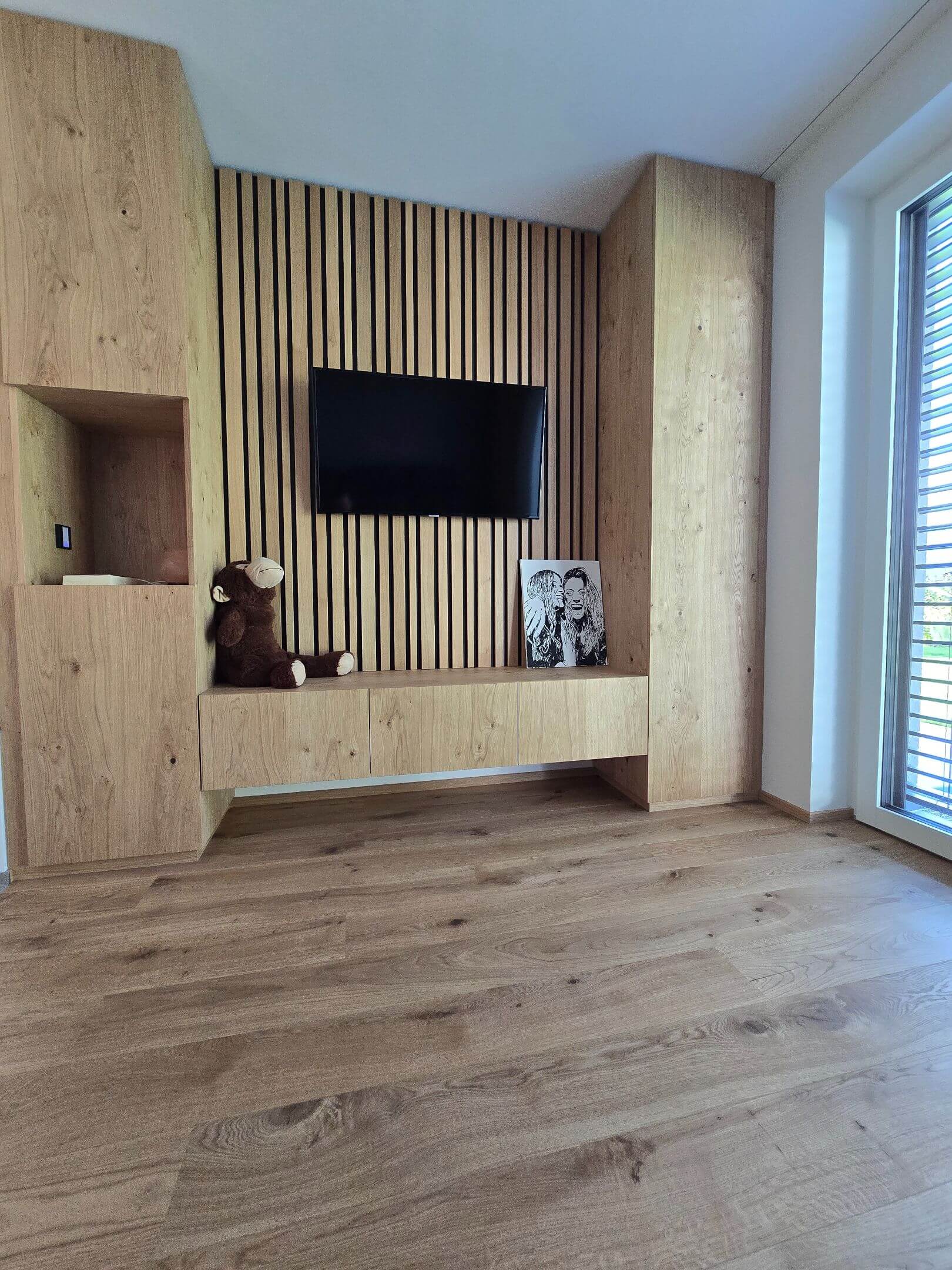 Wohnzimmer mit Holzboden und integrierter Medienwand