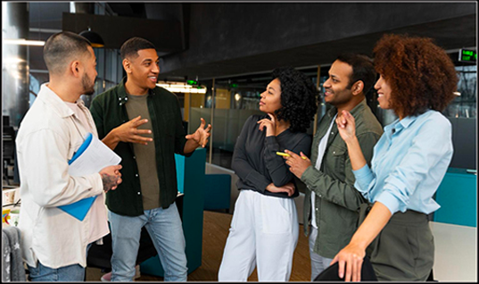 Five diverse young professionals engaged in a lively discussion in a modern office setting.