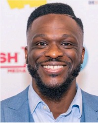 Smiling man with a beard and short afro hairstyle wearing a light blue collared shirt.