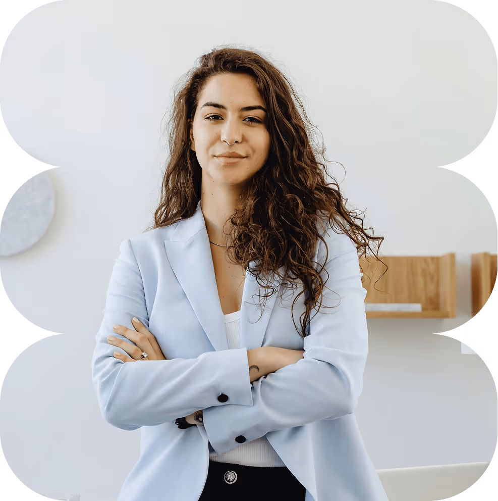 Confident woman with long curly hair, wearing a light blue blazer with arms crossed.