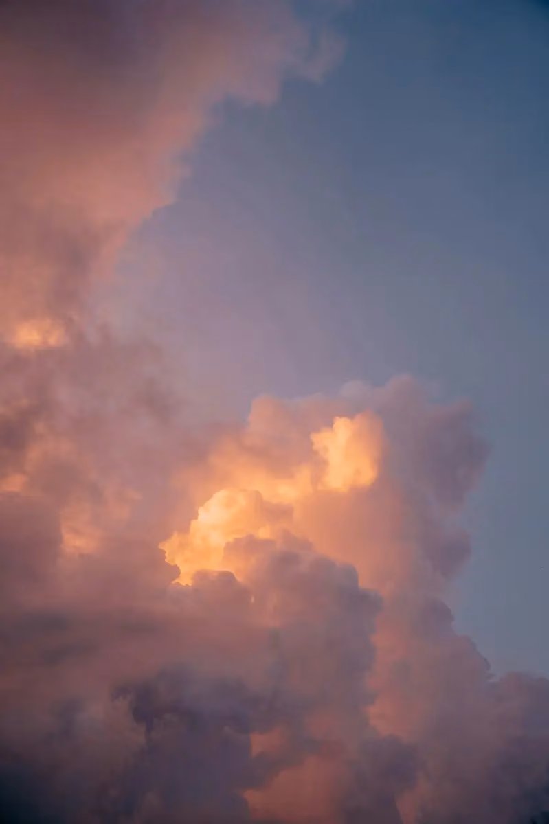 Clouds in the sky illuminated with soft orange and pink hues against a blue background, suggesting a sunset or sunrise.