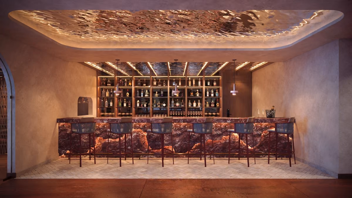 Modern bar with a backlit marble counter in shades of red and purple, six high stools, a fully stocked wooden shelf of liquor bottles, and a ceiling with reflective, wavy glass panels and warm ambient lighting.