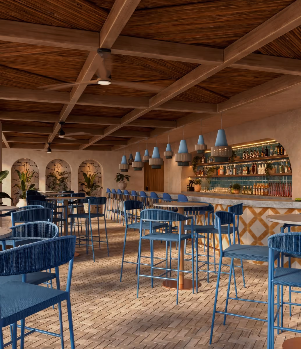Interior of a modern beach club bar with wooden grid ceiling, blue bar stools and chairs, marble-topped tables, hanging blue pendant lights, and a back bar with bottles and plants.