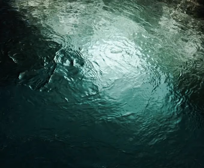 Rippling water surface reflecting light with shades of green and turquoise.