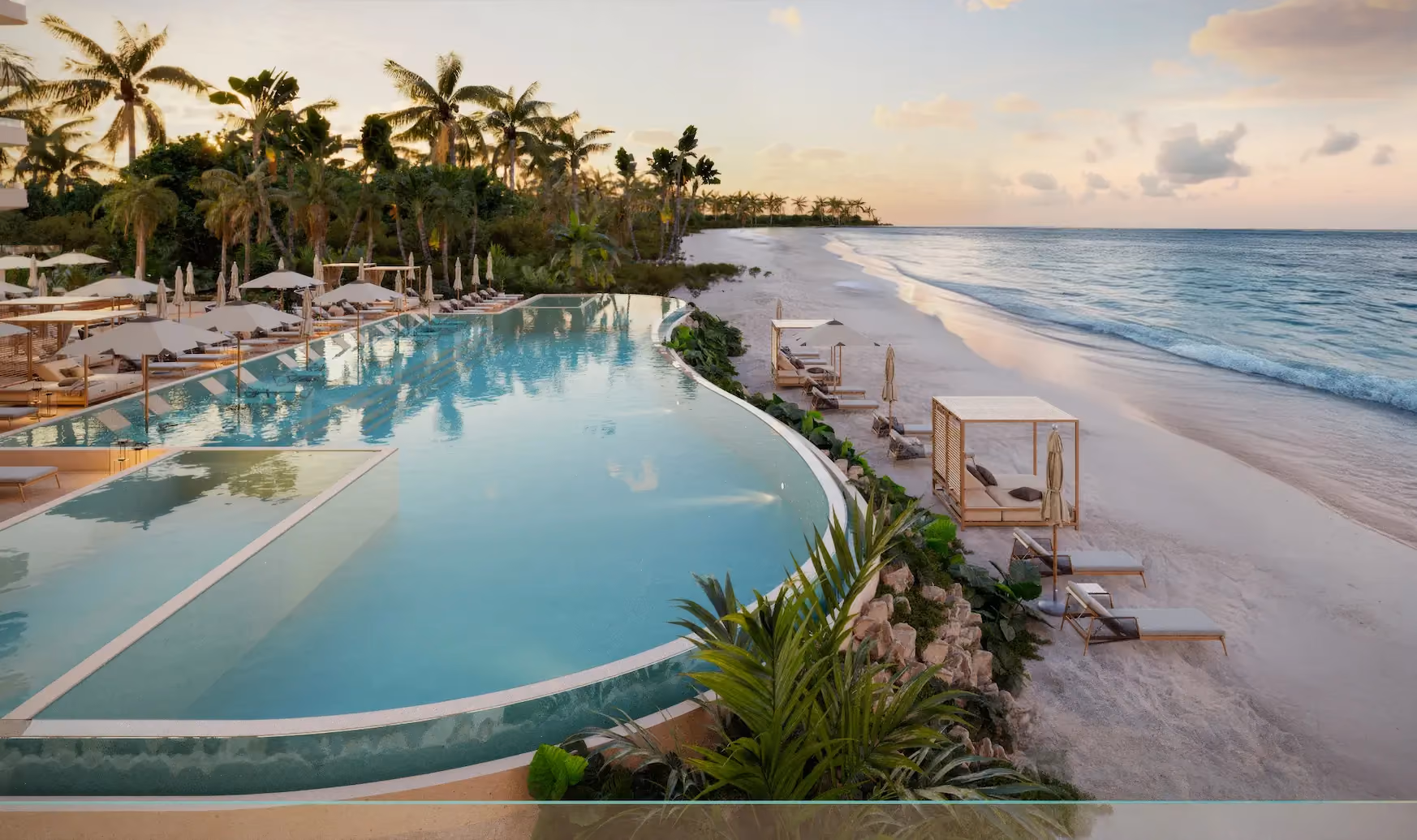 Infinity pool at a beach club overlooking a sandy beach with lounge chairs, cabanas, palm trees, and a calm ocean under a pastel sunset sky.