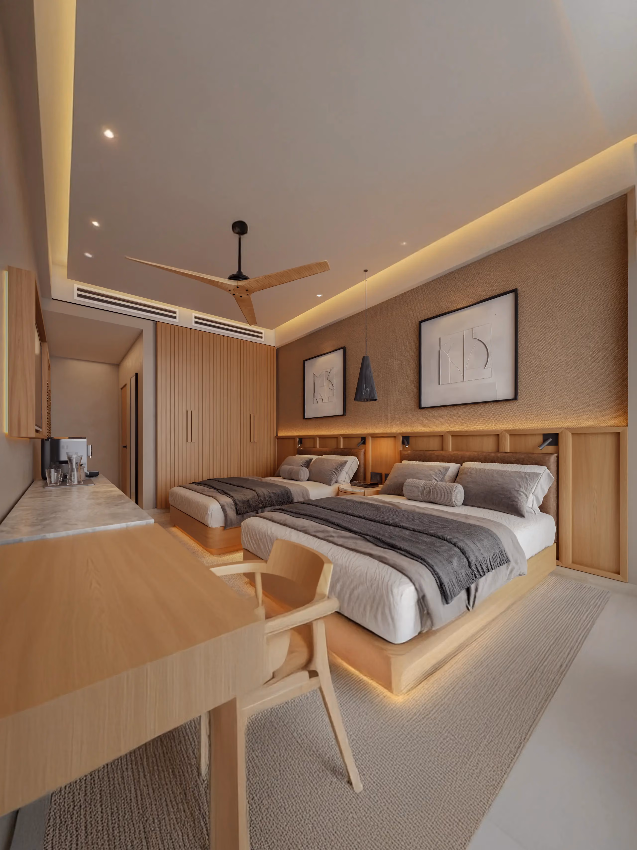 Modern hotel room with two queen beds featuring gray and white bedding, wooden headboards, overhead pendant light, desk with wooden chair, built-in cabinetry, ceiling fan, and warm ambient lighting.