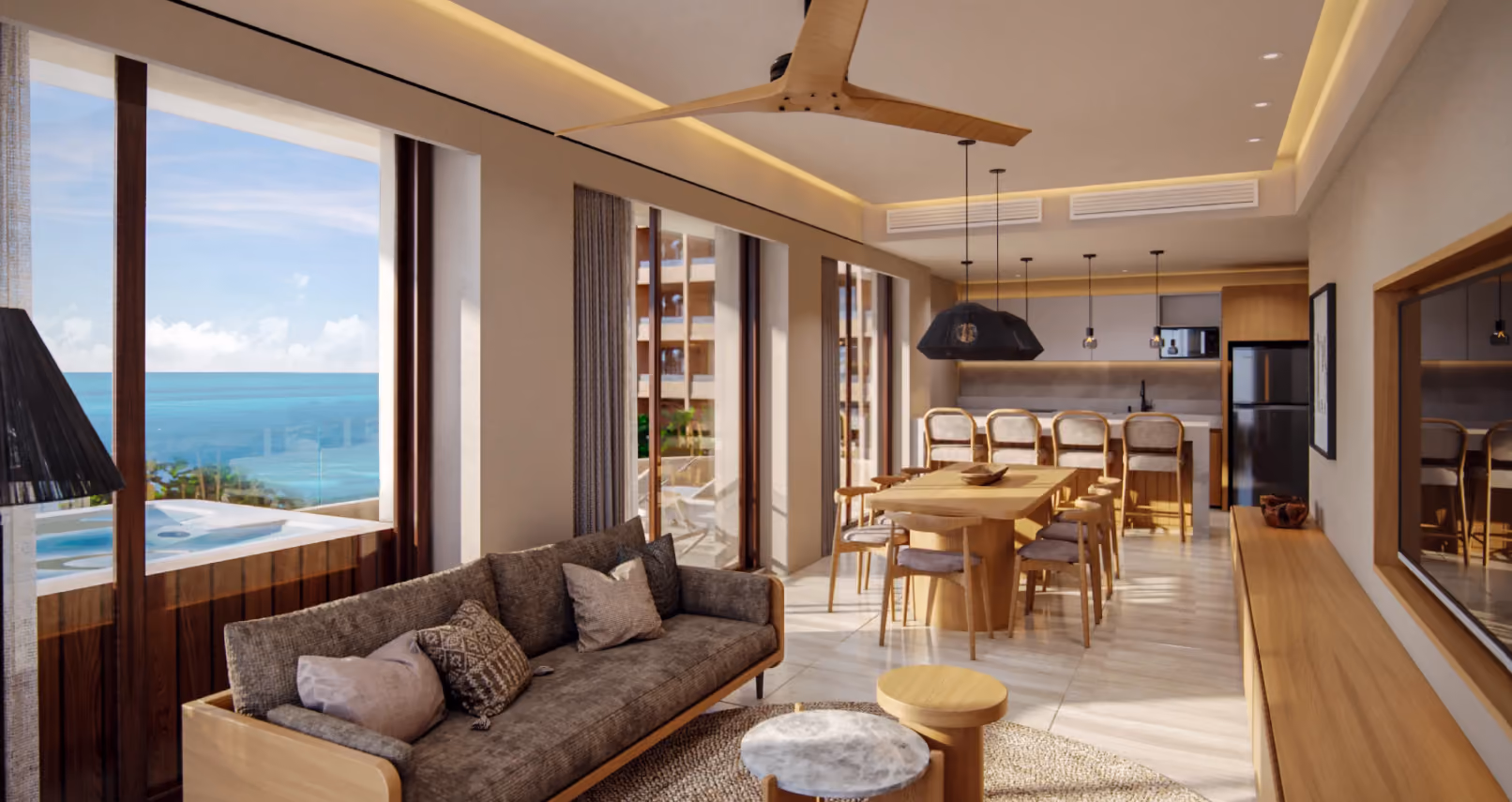 Modern open-concept living and dining area with large windows showing an ocean view, a gray sofa, wooden dining table with chairs, bar stools at a kitchen island, pendant lights, and light wooden accents throughout.