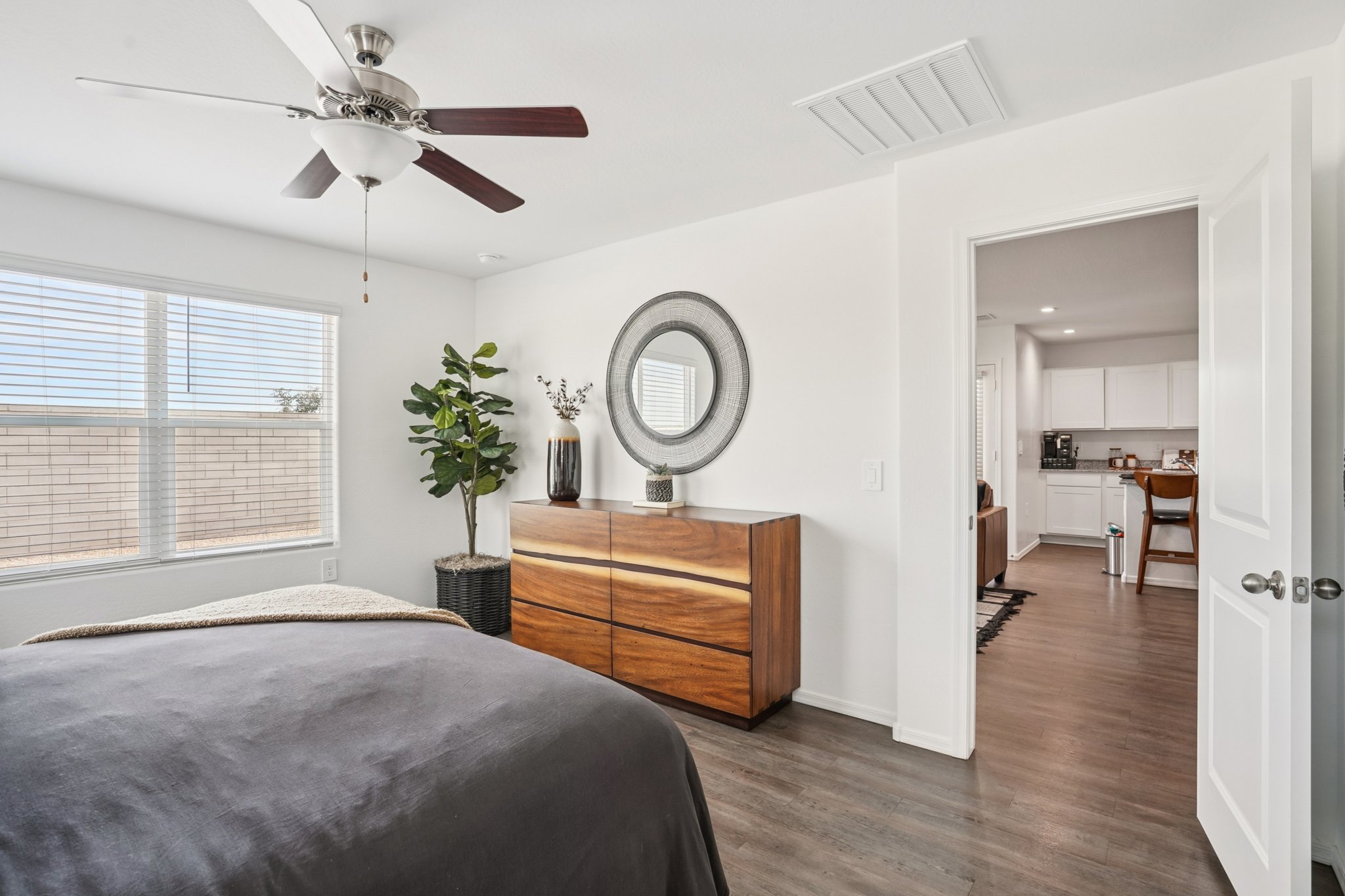 Staged bedroom with dresser and decor, with a view to the main living space