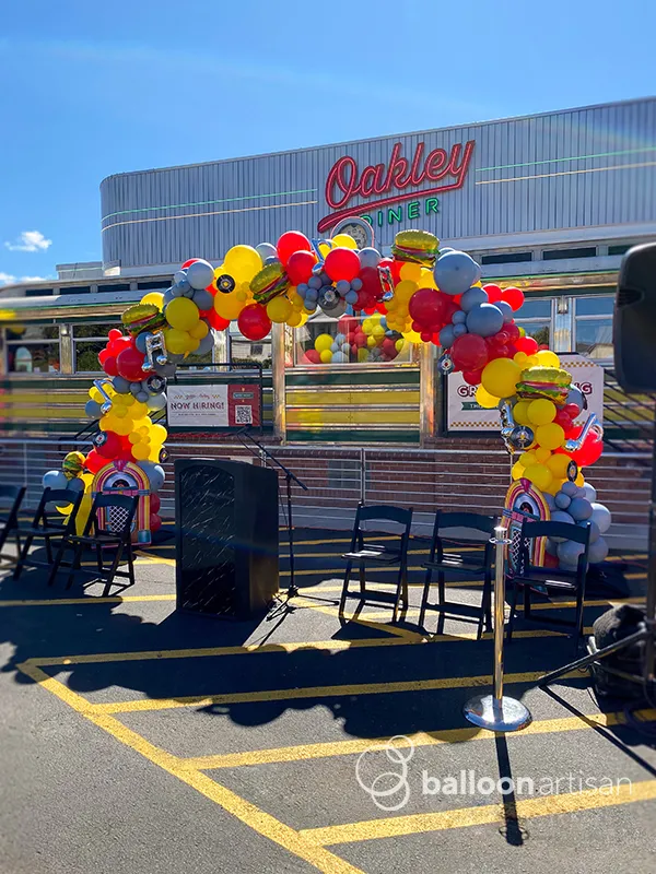 A diner themed balloon arch for a ribbon cutting ceremony makes for a nice balloon backdrop over the speaker podium.