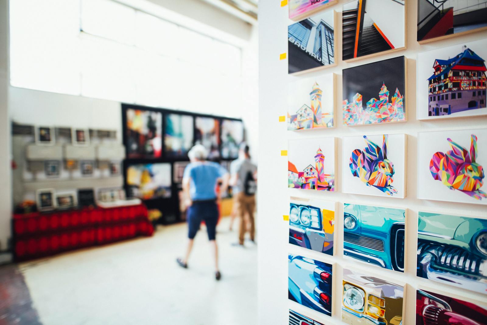 Colorful artwork on display in a gallery with people browsing the exhibition