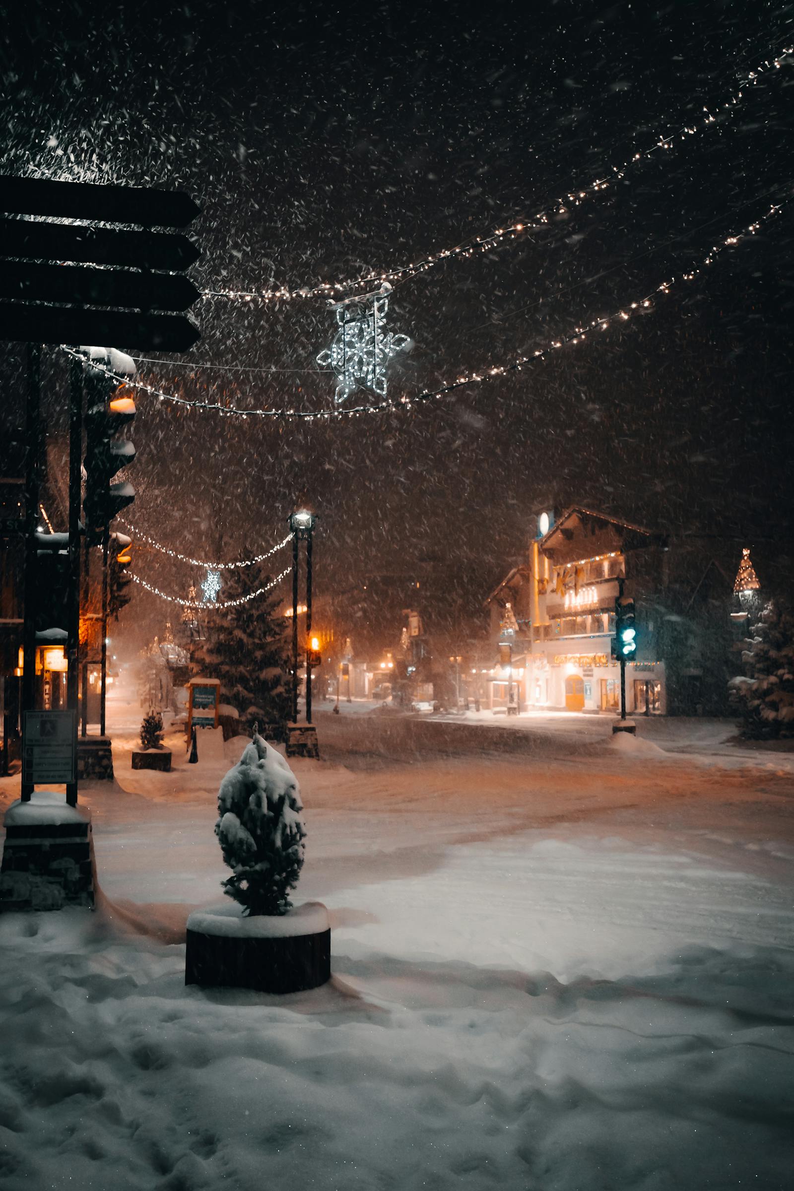 Snowy small-town square at night lit with holiday Christmas lights