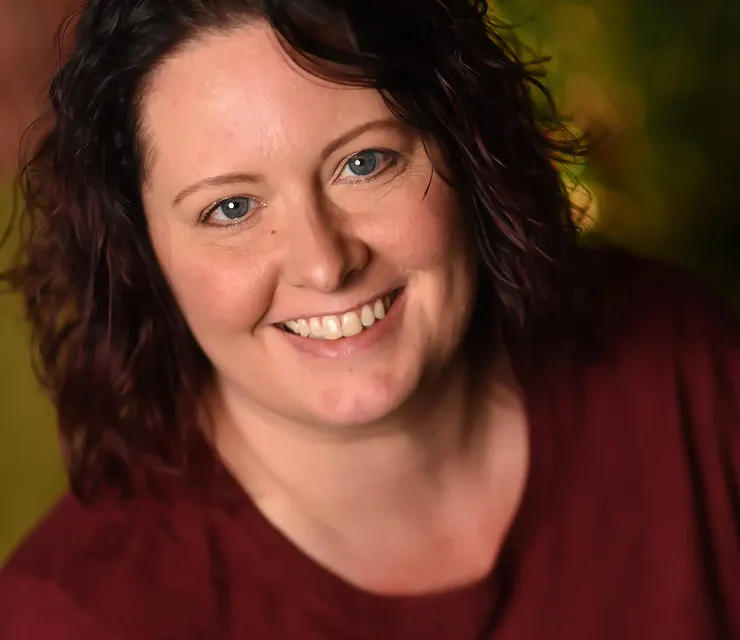 A woman smiling for a picture in a red shirt.