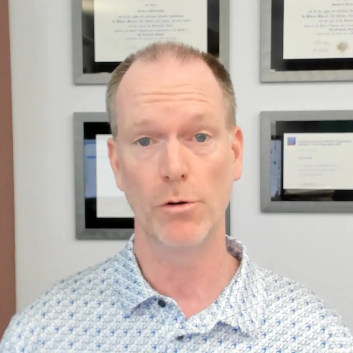 A man is standing in front of a wall with pictures on it.