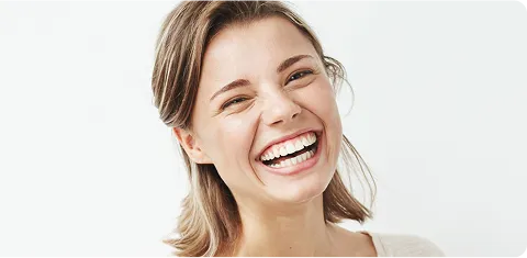Smiling young woman with shoulder-length hair laughing against a white background.