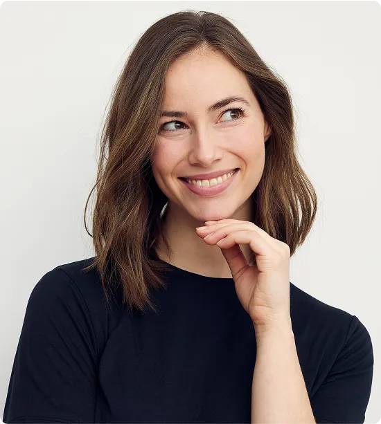 Smiling woman with shoulder-length brown hair wearing a black top, resting her chin on her hand and looking to the side.