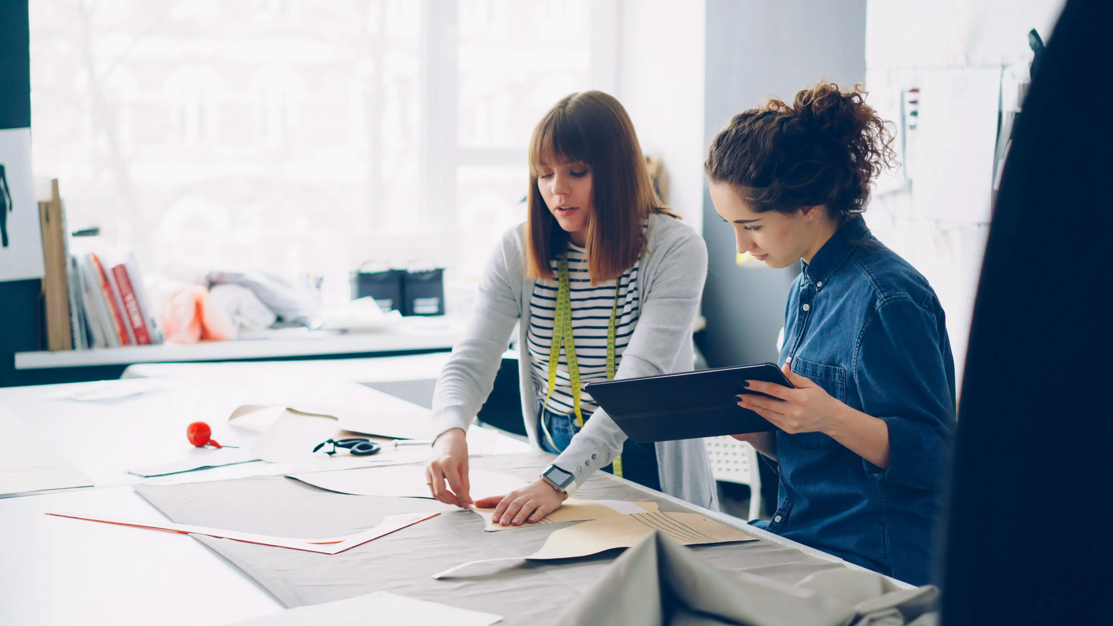 Designer and pattern maker reviewing a sewing pattern together at a work table