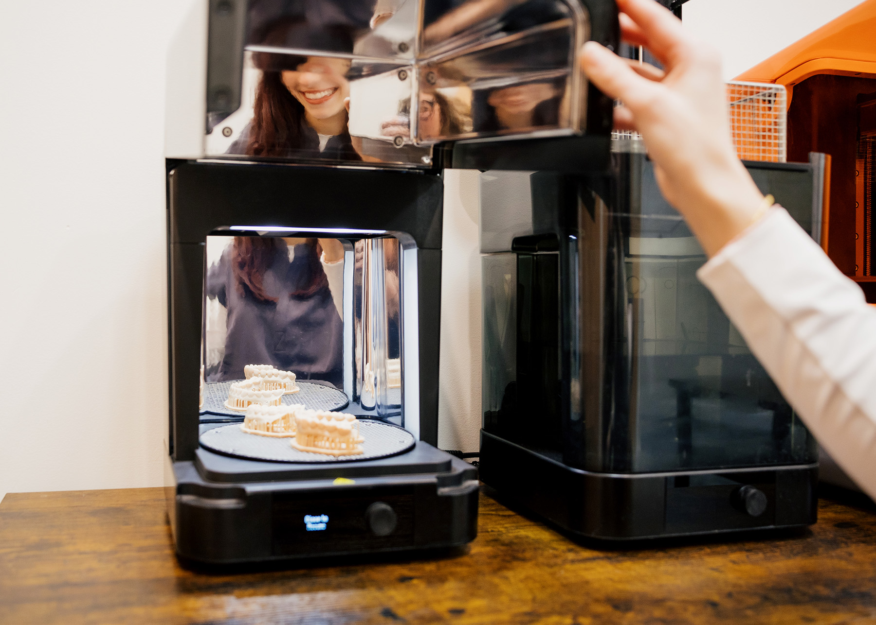3D printer creating dental mold models on a rotating platform with a person operating the machine.