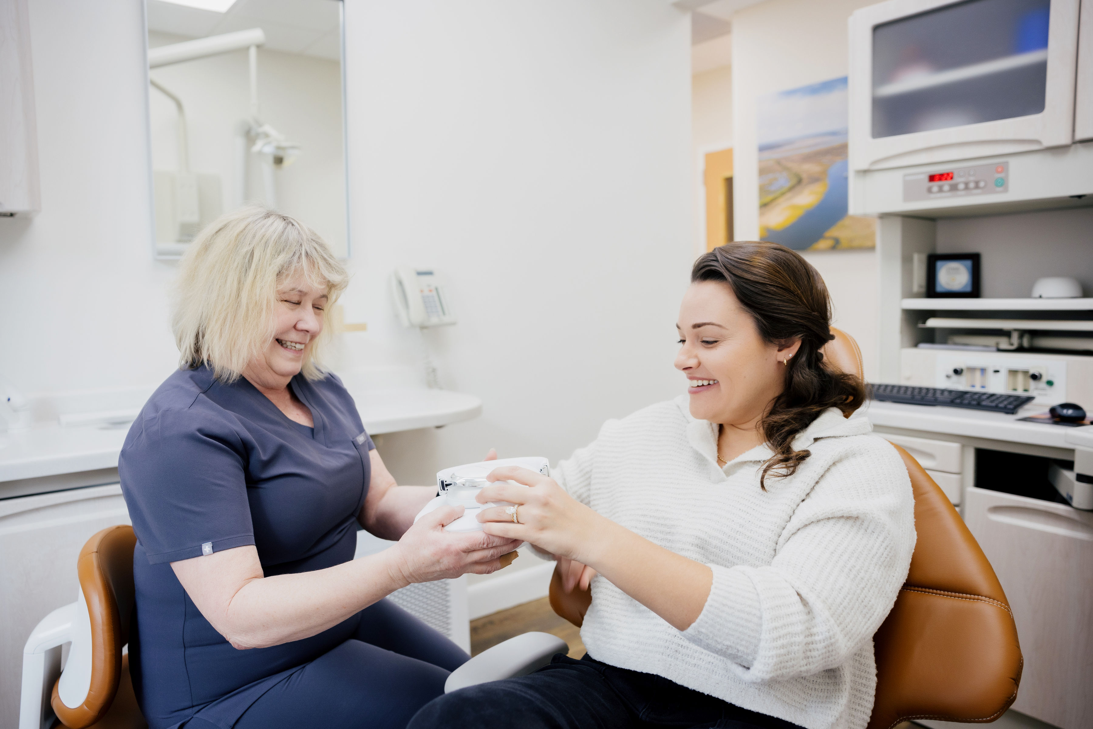 Smiling dental professional and patient exchanging a dental care product in a dental office.