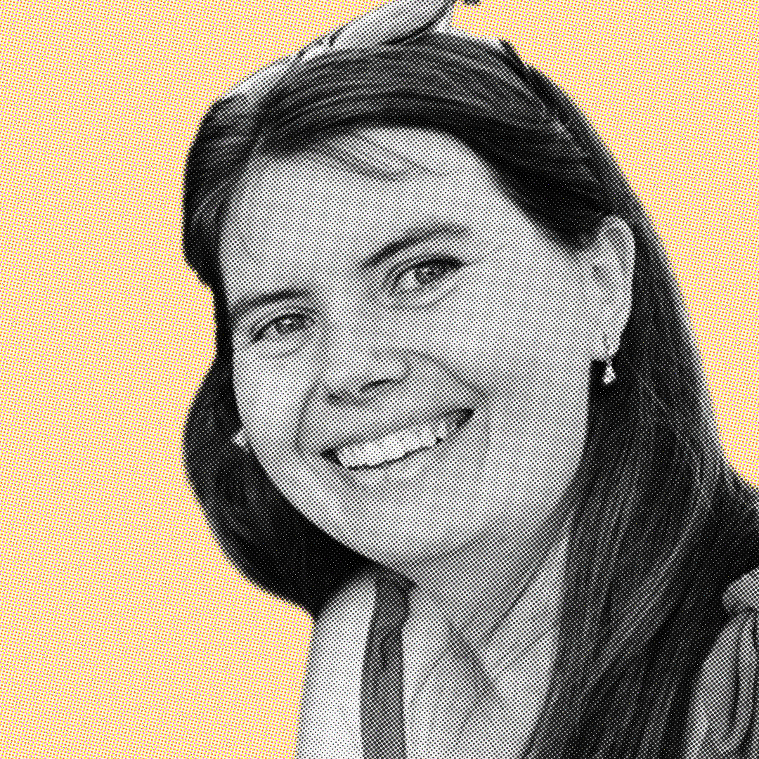 Smiling woman with long hair wearing earrings and sunglasses on her head against a solid yellow background.