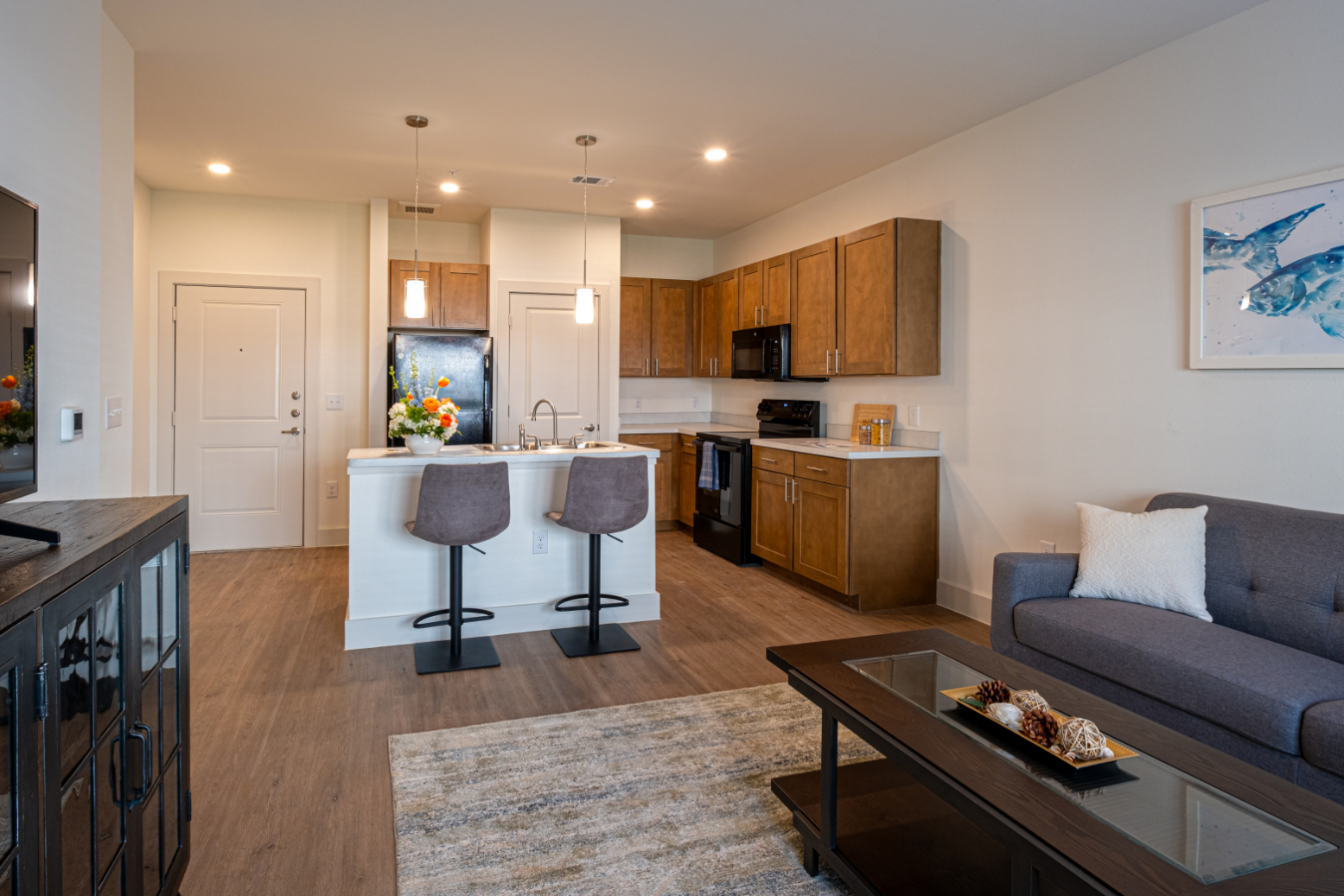 Living area with sofa and coffee table and view into kitchen with island 