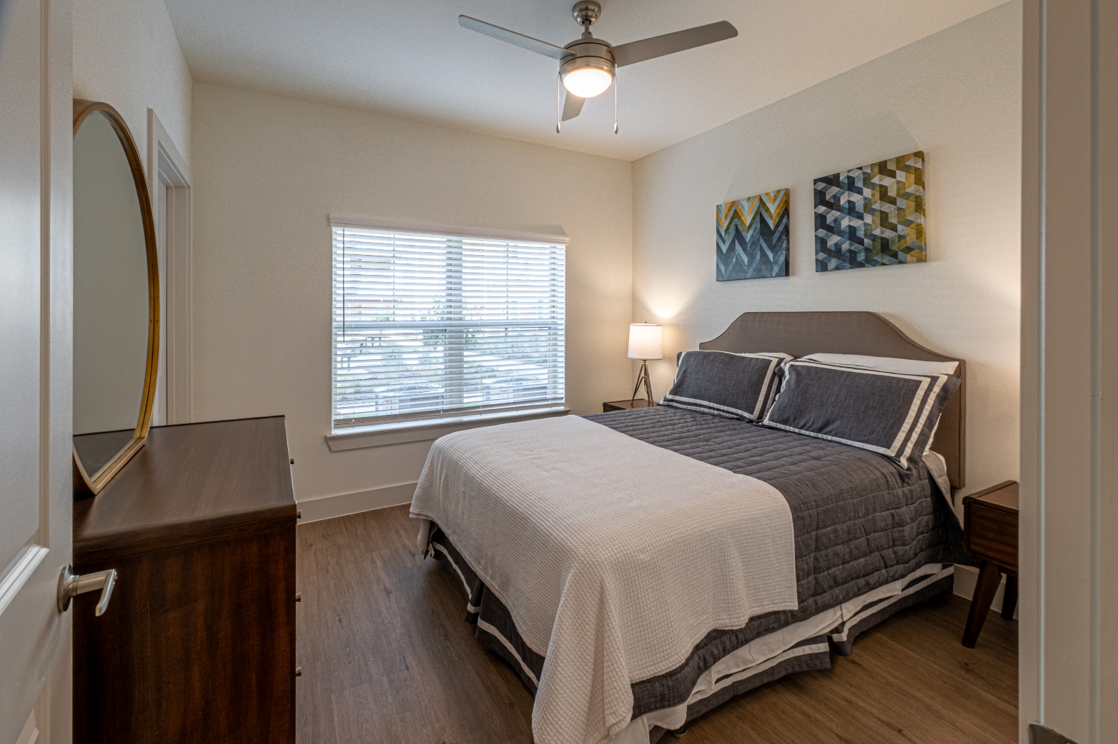 Bedroom with bed, dresser, ceiling fan, and large window