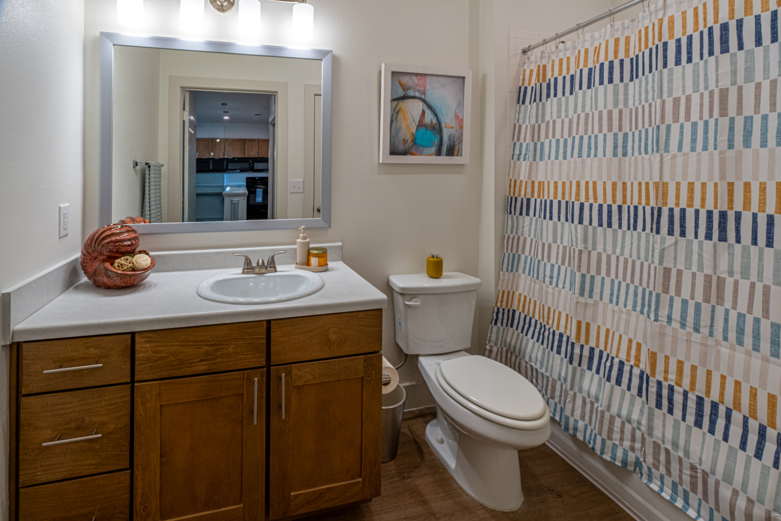 Bathroom with vanity with brown cabinets, mirror and shower tub combo with curtain