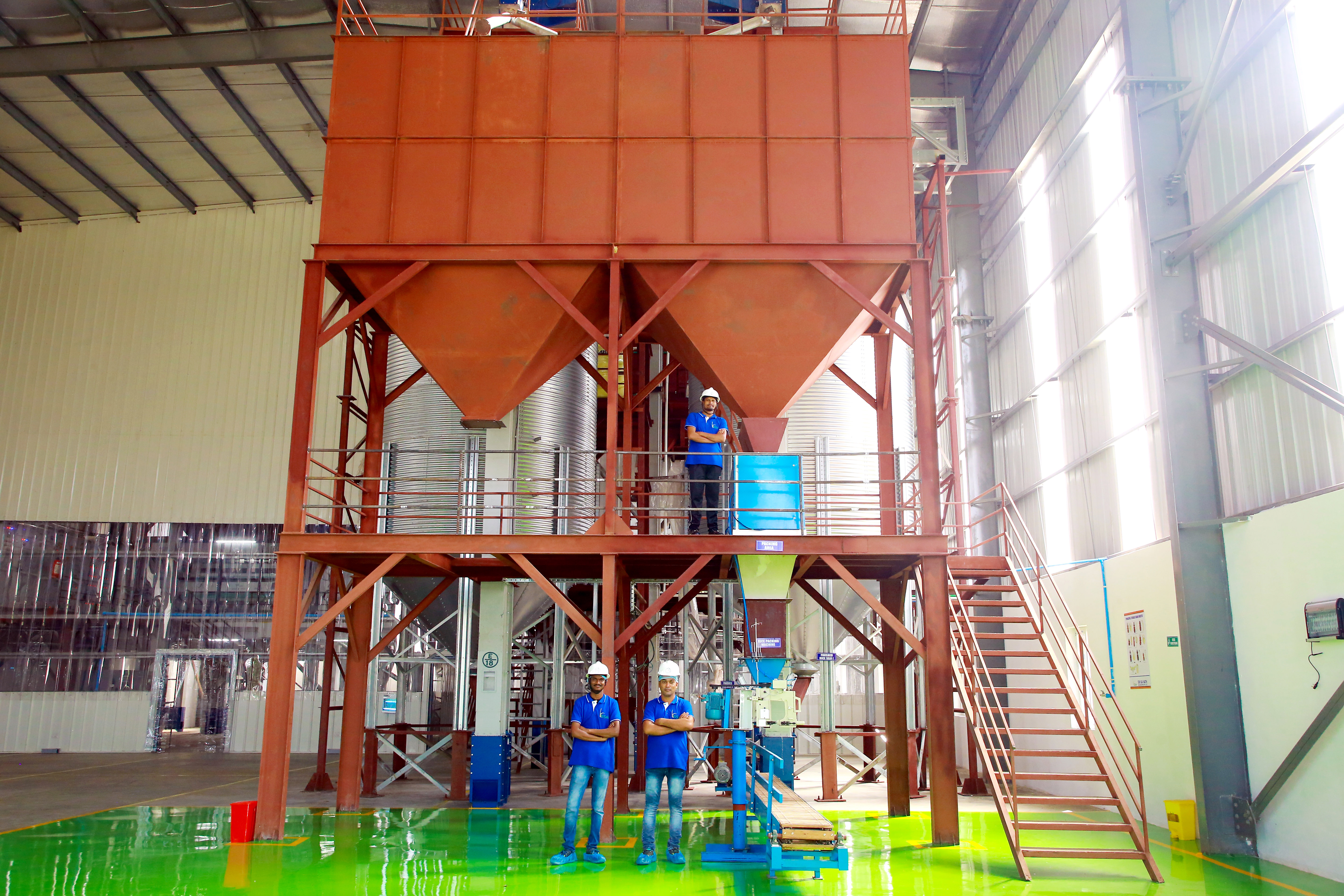 An image of three employees standing infront of a sifting machine