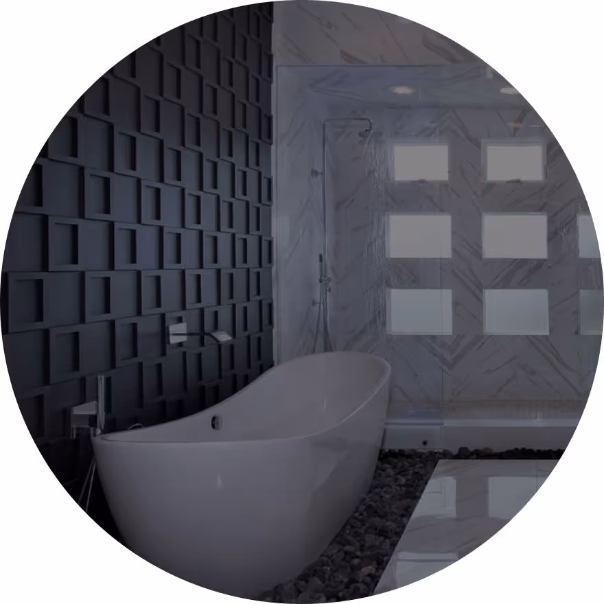 A modern bathroom featuring a freestanding white bathtub, dark textured wall tiles, and a glass shower with white marble accents. The floor includes pebbles and glossy tiles.